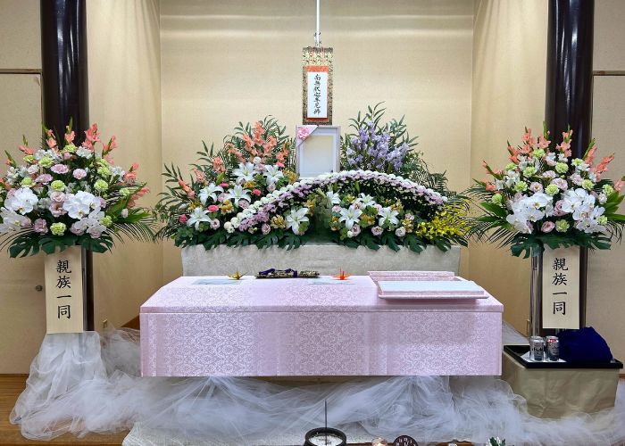 和歌山市斎場小ホール式場内で祭壇を設置。ピンクのお棺と祭壇の色合いが合って優しく、故人が女性らしい雰囲気で飾られています。